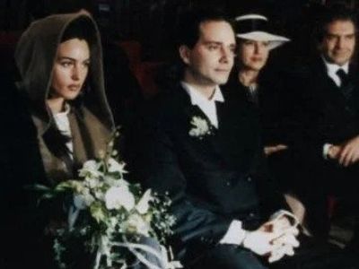 Both Claudio Carlos Basso and Monica Bellucci are in their wedding dress as they are sitting quietly.